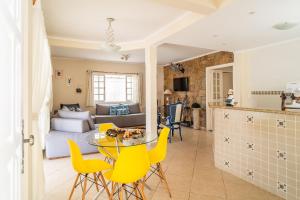 a kitchen and living room with yellow chairs and a table at Maravilhosa casa no Cond. fechado Morada da Praia in Boracéia