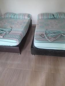 dwa łóżka siedzące obok siebie na drewnianej podłodze w obiekcie CLUB CAMPESTRE EL DESPERTAR DE LAS AVES 