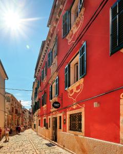 un edificio rosso sul lato di una strada di Hotel Angelo d'Oro a Rovigno (Rovinj)