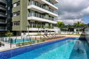 uma piscina com espreguiçadeiras e um edifício em Apto charmoso c/ varanda a 150m da praia ABC403 em Itajaí
