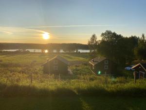 a sunset over a field with houses and a lake at Ulvsby Ranch in Karlstad