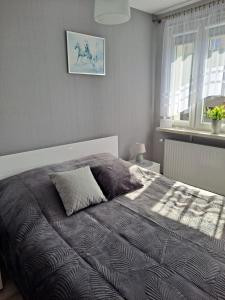 a bedroom with a bed with a blanket and a window at Studio Zabobrze in Jelenia Góra