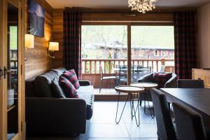 a living room with a couch and a table and chairs at Les Cimes in La Clusaz