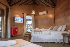 a bedroom with two beds and a tv on the wall at Mansur Hotelaria de Charme in Luis Correia