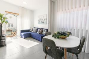ein Wohnzimmer mit einem Tisch und einem blauen Sofa in der Unterkunft Casa Brilhante - Sunny Delight in Nazaré