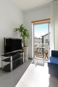 ein Wohnzimmer mit einem TV und einer Glasschiebetür in der Unterkunft Casa Brilhante - Sunny Delight in Nazaré