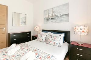 ein Schlafzimmer mit einem Bett mit Kissen und einem Segelboot an der Wand in der Unterkunft Casa Brilhante - Sunny Delight in Nazaré