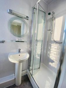 a bathroom with a sink and a shower with a mirror at Cwtch Guesthouse in Llandudno
