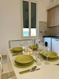 een keukentafel met groene borden en wijnglazen bij Guest House (15 min metro dal Duomo) in Milaan