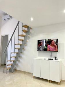 Guest House (15 min metro dal Duomo) في ميلانو: غرفة معيشة بها درج وتلفزيون على الحائط