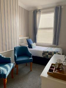 a bedroom with a bed and two chairs and a window at Cwtch Guesthouse in Llandudno