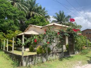una pequeña casa con flores rojas en una valla en Casa dos Paulistas - Ilha de Boipeba, en Isla de Boipeba