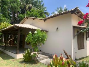 una casa blanca con porche y algunas plantas en Casa dos Paulistas - Ilha de Boipeba, en Isla de Boipeba