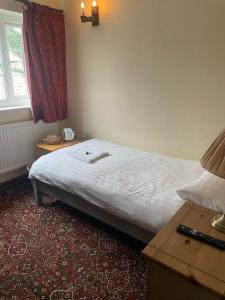 a bedroom with a bed and a table and a window at The White Hart Hotel in Liskeard