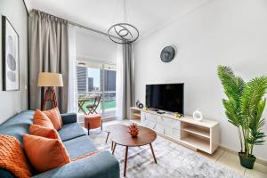 a living room with a blue couch and a tv at StoneTree - 1BR apartment with Lake View in Dubai