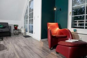 a living room with a red arm chair and a chair at Modernes Apartment in Potsdam-Golm - 2 Zimmer - Balkon - Beamer - Disney Plus in Potsdam