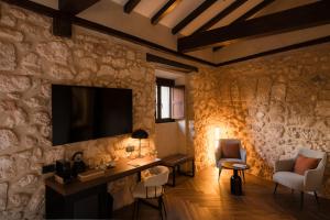 a living room with a tv on a stone wall at Castilla Termal Brihuega in Brihuega