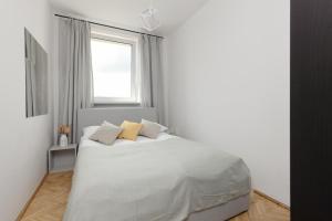 a white bedroom with a white bed with yellow pillows at Family Apartment near Old Town by Renters in Warsaw