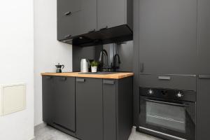 a kitchen with black cabinets and a stove at Family Apartment near Old Town by Renters in Warsaw