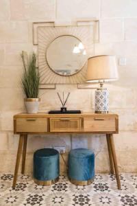 a desk with a mirror and a lamp and stools at Birgu 3 in Cospicua