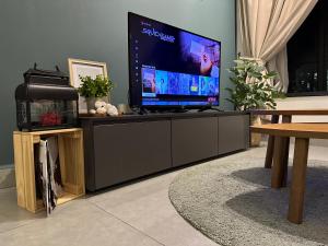 a flat screen tv sitting on top of a entertainment center at Cozy Kanvas Soho Suites in Cyberjaya