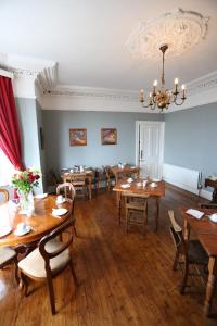 a dining room with tables and chairs and a chandelier at Rolling Wave Guesthouse in Bundoran