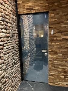 a bathroom with a glass door in a brick wall at City Spa Nijmegen in Nijmegen