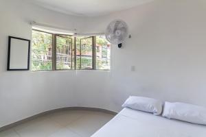 Cette chambre blanche dispose d'un lit et d'un ventilateur. dans l'établissement CASA TURISTICA MACHU PICCHU MEDELLIN, à Medellín