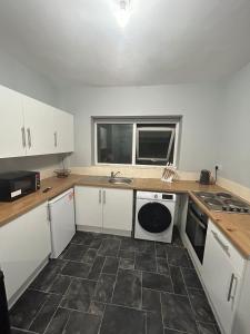 a kitchen with white cabinets and a sink and a dishwasher at High Street House in Bath
