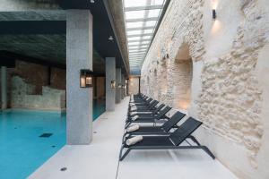 a row of chaise lounge chairs next to a pool at Castilla Termal Brihuega in Brihuega +29 photos