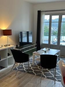 - un salon avec une table, des chaises et une télévision dans l'établissement Appartement Design X - Hyper Centre - Parking Privé - Quimper, à Quimper