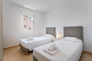 two beds in a room with white walls and a window at Duquesa Regent 2435 Wonderful seaviews duplex in Manilva +28 photos