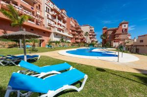 a resort with a swimming pool and two chairs and an umbrella at Duquesa Regent 2435 Wonderful seaviews duplex in Manilva