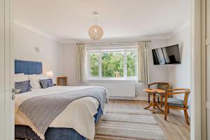 a bedroom with a bed and a window and a chair at Conifers in Lyme Regis
