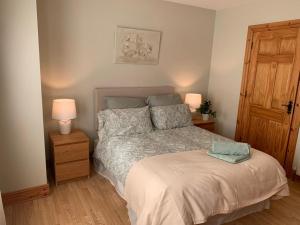 a bedroom with a bed with two lamps and a door at Elm Park Escape - 4 bed self-catering holiday home in Buncrana