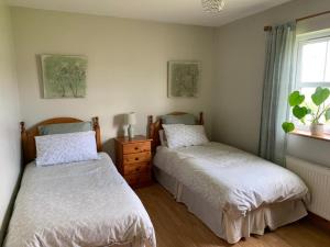 a bedroom with two beds and a window at Elm Park Escape - 4 bed self-catering holiday home in Buncrana