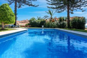 een zwembad met blauw water in een tuin met bomen bij Belgravia Club Estepona in Estepona