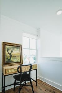 una scrivania con sedia in una stanza con un dipinto di Marsh Hotel a New Orleans