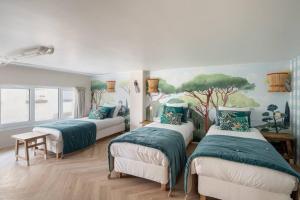 ein Schlafzimmer mit 3 Betten und einem Wandgemälde in der Unterkunft Branded New Loft Riviera Style - 8 guests - Vanves in Vanves
