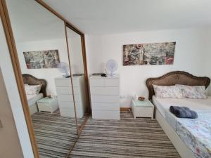 a bedroom with a mirror and a bed and a bed and dresser at Entire Lovely 2 Bedroom Apartment in Southend-on-Sea