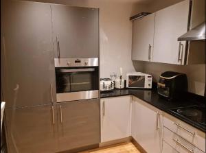 una cucina con armadi bianchi e frigorifero in acciaio inossidabile di Entire Lovely 2 Bedroom Apartment a Southend-on-Sea