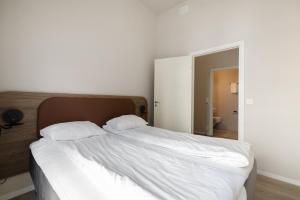 Maya Apartments - Parkveien في أوسلو: سرير ابيض ومخدتين عليه في غرفة النوم