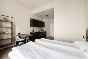 a room with four beds and a table and a kitchen at Maya Apartments - Parkveien in Oslo