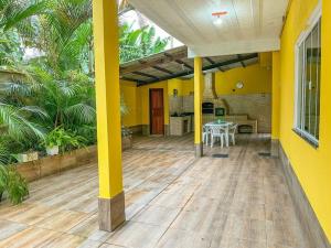 ein gelbes Haus mit einer Terrasse mit einem Tisch in der Unterkunft Casa com churrasqueira e piscina, perto de riacho in Angra dos Reis