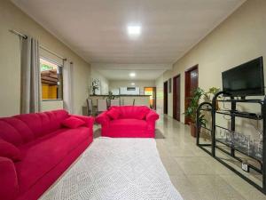 uma sala de estar com um sofá vermelho e uma televisão em Casa com churrasqueira e piscina, perto de riacho em Angra dos Reis