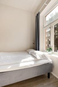 a white bedroom with a bed and a window at Maya Apartments - Parkveien in Oslo