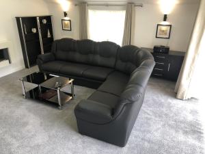 a black leather couch in a living room with a table at Castle House Holiday Home in Chapel en le Frith