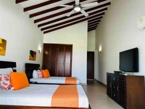 1 dormitorio con 2 camas y TV de pantalla plana en ¡Fantastic Beach House!, en Arroyo de Piedra