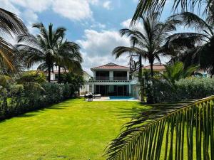 una casa con un patio verde con palmeras en ¡Fantastic Beach House!, en Arroyo de Piedra