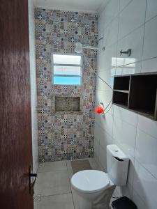 a bathroom with a toilet and a tile wall at Casa de praia in Mongaguá